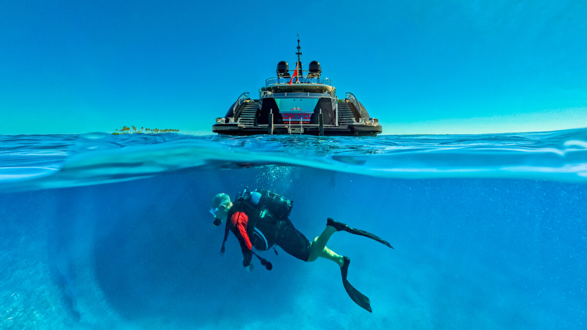 Scuba diver swimming with OKTO in the background, Cuba Yacht Charter, Cuba Yacht Charter Itinerary